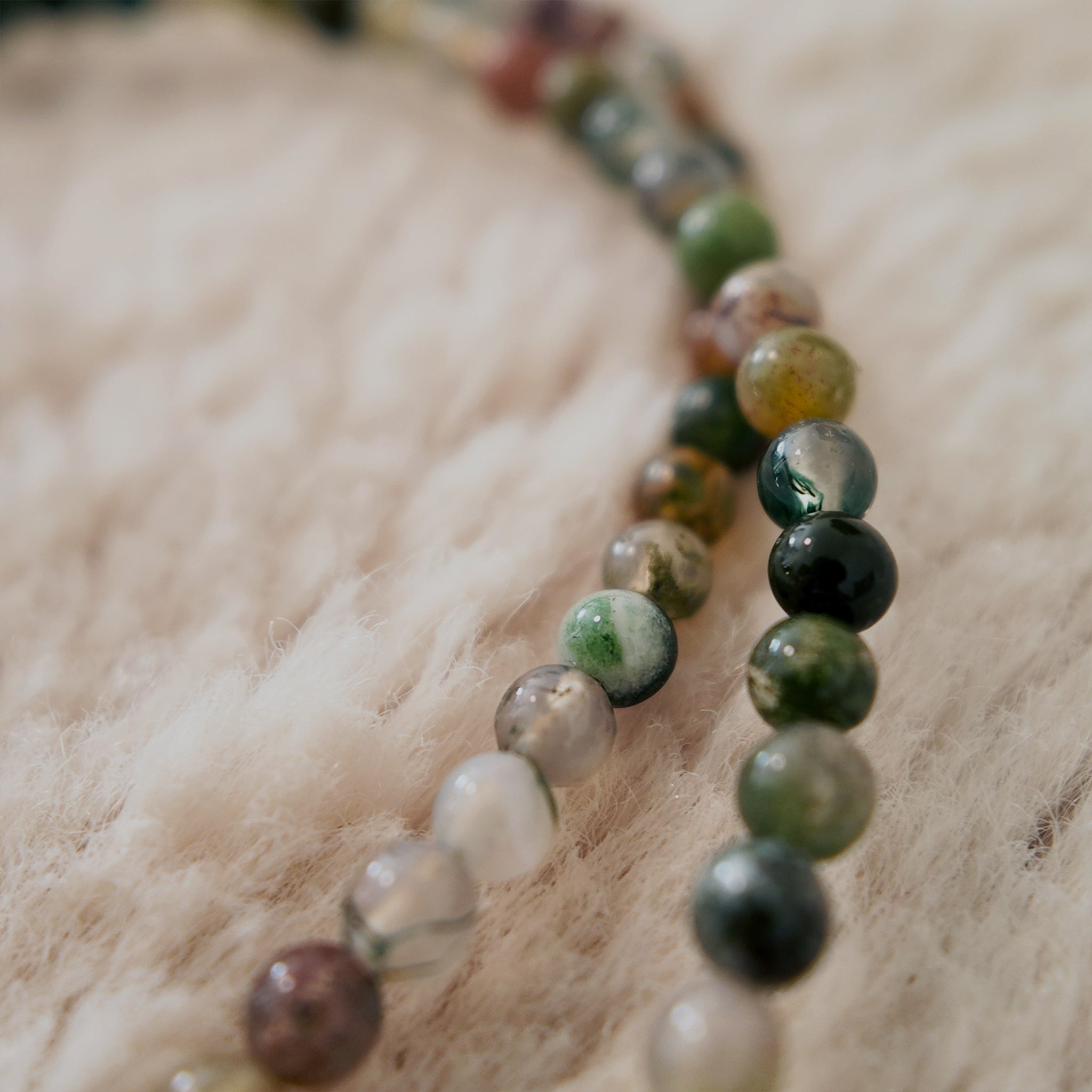 The "Quiet Path," a minimalist, artisan-made beaded choker necklace, strung with tiny, natural agate seed beads in a mix of earthy green tones.