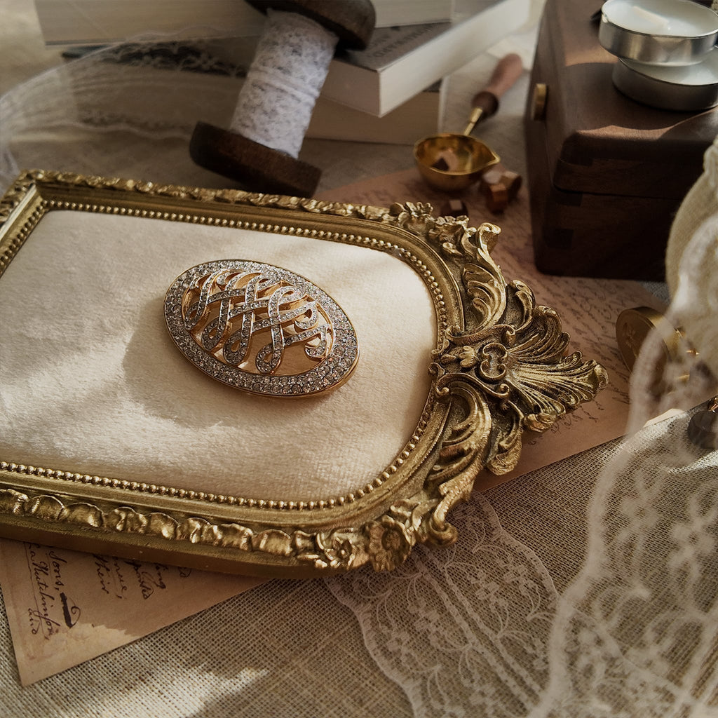 The "WW" brooch styled next to a photo of Wallis Simpson to emphasize its historical significance as a symbol of the 20th century's greatest royal love story.