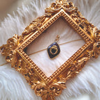 The amethyst "sword-flower" charm styled on a piece of dark velvet to emphasize its "Royal Dignity" aesthetic and its identity as a powerful protection amulet.