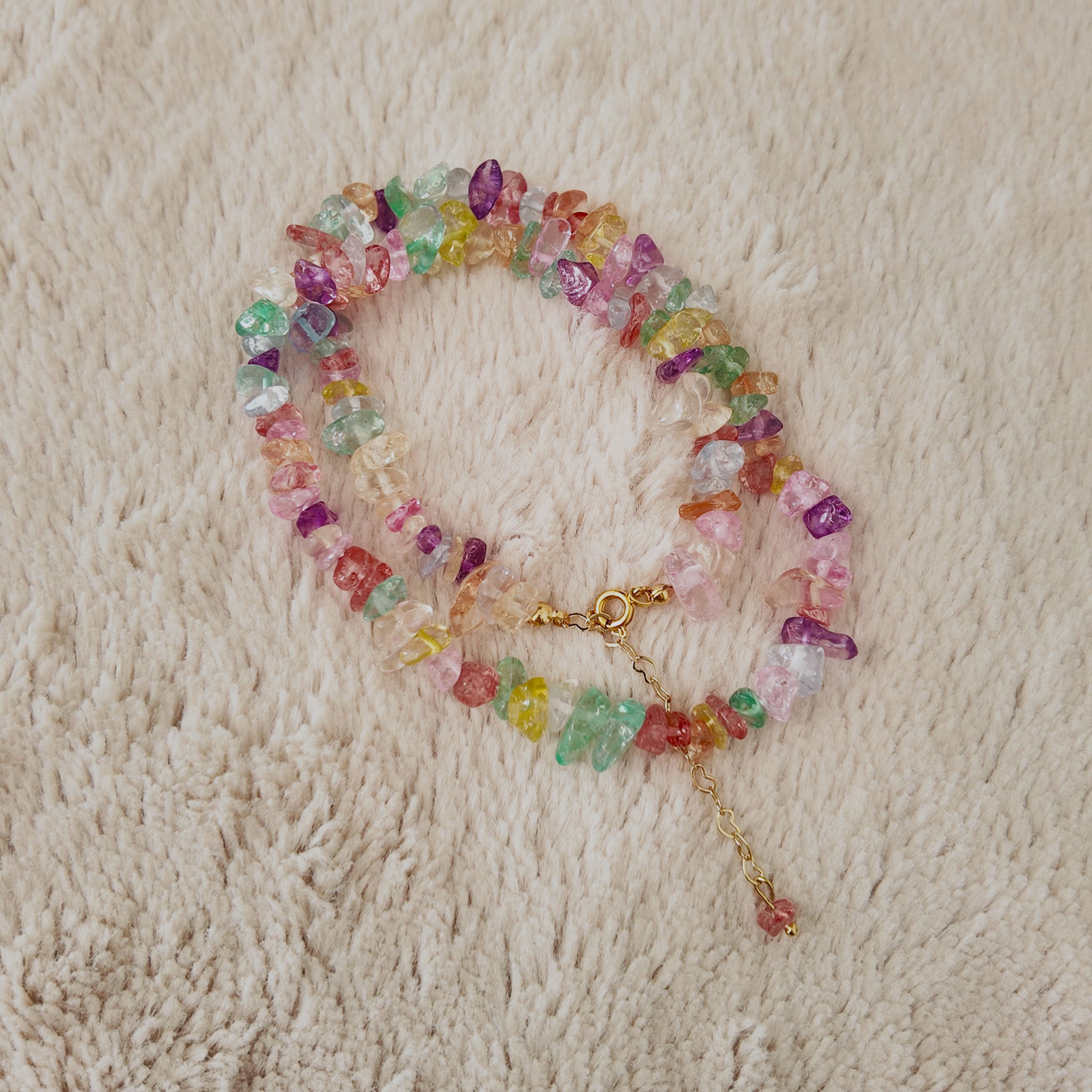 The stone chip necklace styled as a layering piece with a gold chain, demonstrating its versatility and its role in the "Dopamine Dressing" trend.